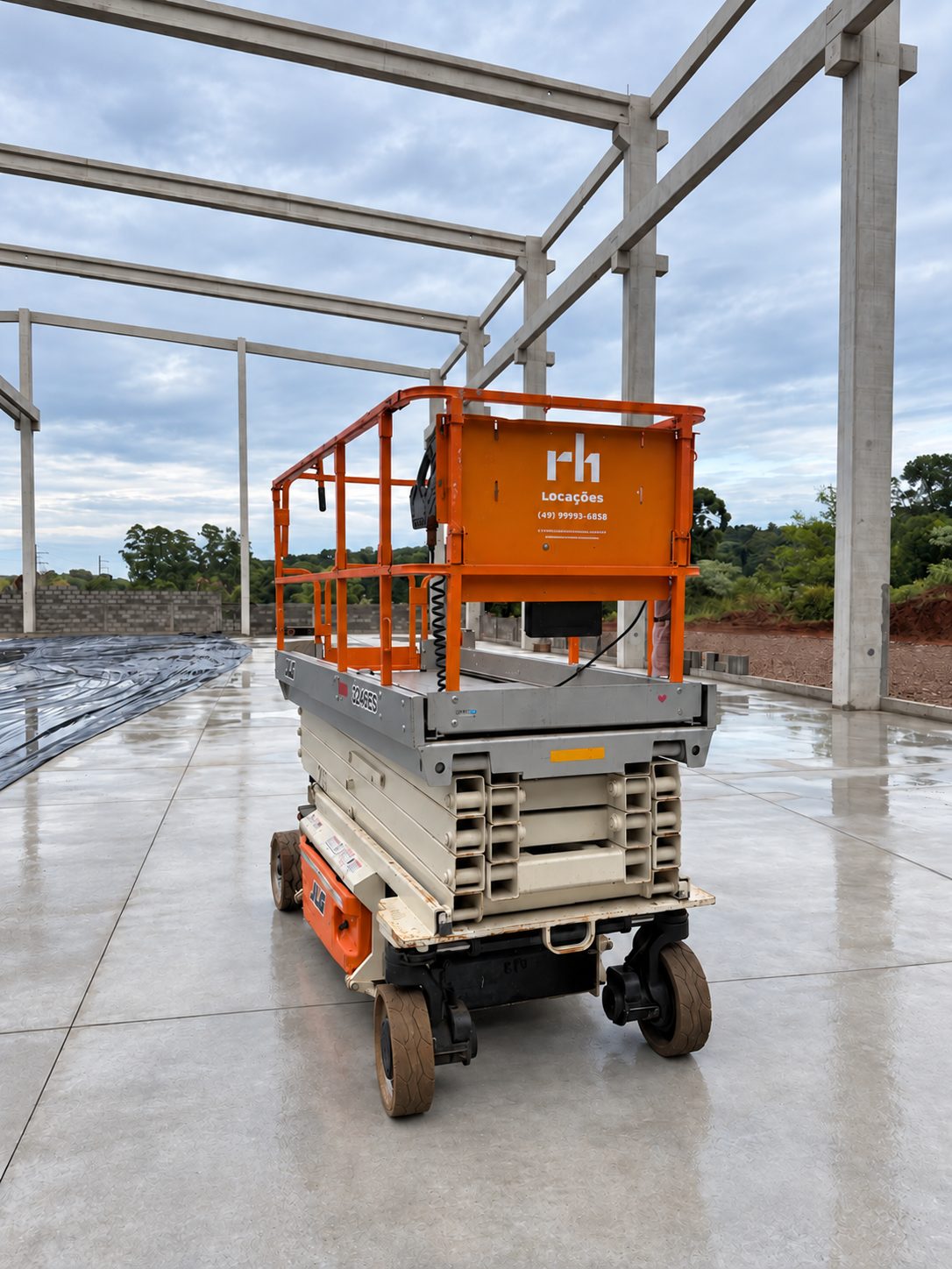 Plataforma tesoura JLG 3246ES da rh Locações no piso de um galpão em construção